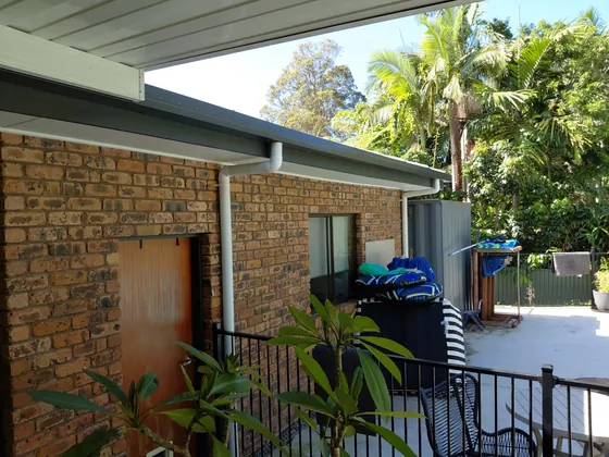 New guttering and eave on a brick home beside a tropical garden