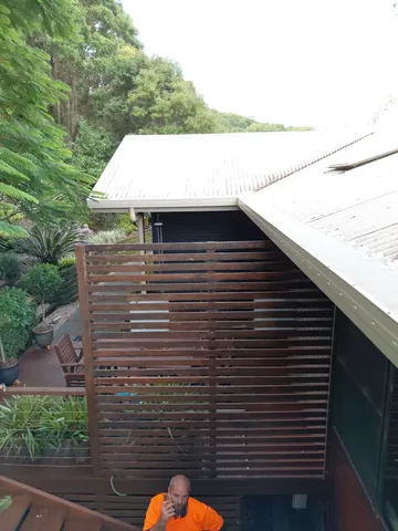 Summerland crew member alongside a metal roof and gutter