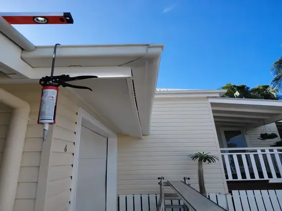 Spirit level checking fall on new guttering during a roof repair